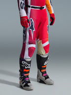 Spodnie Alpinestars 2026 Racer Portl, spodnie motocrossowe, czerwone, jasnoszare i ciemnoszare, noszone z pasującymi czerwonymi rękawicami i wielokolorowymi butami motocrossowymi, z wyraźnymi logotypami Alpinestars i wzmocnionymi panelami do wyścigów terenowych.