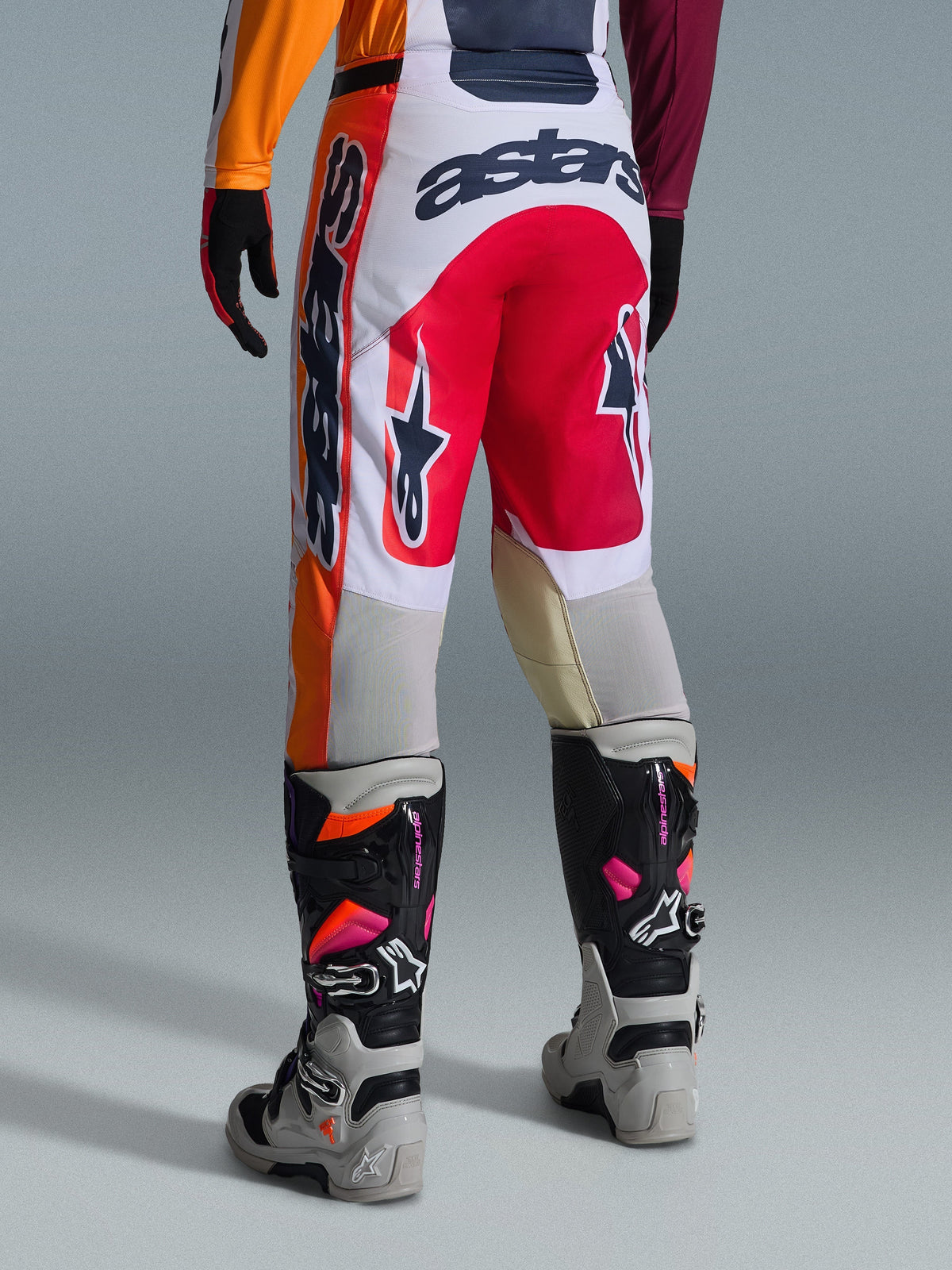 Alpinestars 2026 Racer Portl Pants, spodnie motocrossowe, czerwone, jasnoszare i ciemnoszare, widok z tyłu z wyraźnym brandingiem i detalami logo, w zestawie z dopasowanymi butami i rękawicami motocrossowymi, profesjonalna odzież do wyścigów terenowych.