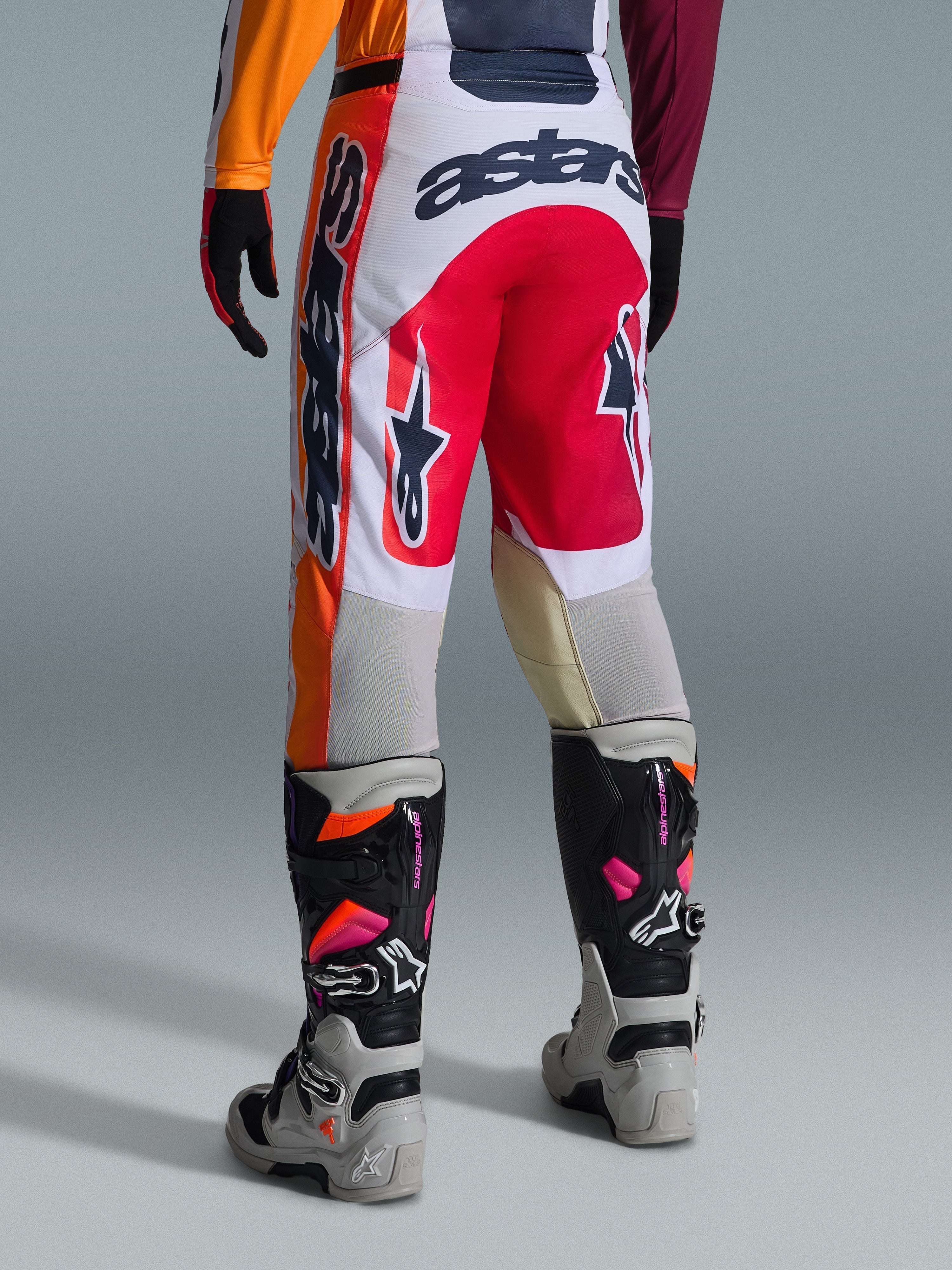 Alpinestars 2026 Racer Portl Pants, spodnie motocrossowe, czerwone, jasnoszare i ciemnoszare, widok z tyłu z wyraźnym brandingiem i detalami logo, w zestawie z dopasowanymi butami i rękawicami motocrossowymi, profesjonalna odzież do wyścigów terenowych.