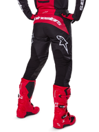 Alpinestars 2025 Fluid Haul Gear Set, widok z tyłu, czarno-czerwone spodnie motocrossowe z dużymi białymi logotypami, pasująca koszulka i intensywnie czerwone buty Tech 7, dopasowany zestaw wyścigowy off-road