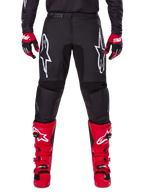 Zestaw Alpinestars 2025 Fluid Haul, czarne spodnie motocrossowe z białymi logo Astars na udach, jaskrawoczerwone buty i czerwono-czarne rękawice, dopasowany strój do wyścigów terenowych