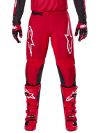 Alpinestars 2025 Fluid Haul Pants, spodnie motocrossowe, jaskrawoczerwone i czarne, z dużymi białymi logo na udach i czarnymi panelami po wewnętrznej stronie nogawek, noszone z pasującymi czerwonymi butami i rękawicami, sportowy krój zapewniający wydajność w motocrossie
