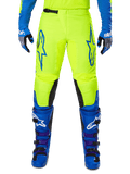 Alpinestars 2025 Fluid Haul Pants, spodnie motocrossowe, jaskrawo żółte i niebieskie, noszone z pasującymi rękawicami i butami, czarne panele wewnętrzne na kolanach, wyrazisty niebieski branding na udach, sportowy ergonomiczny design.