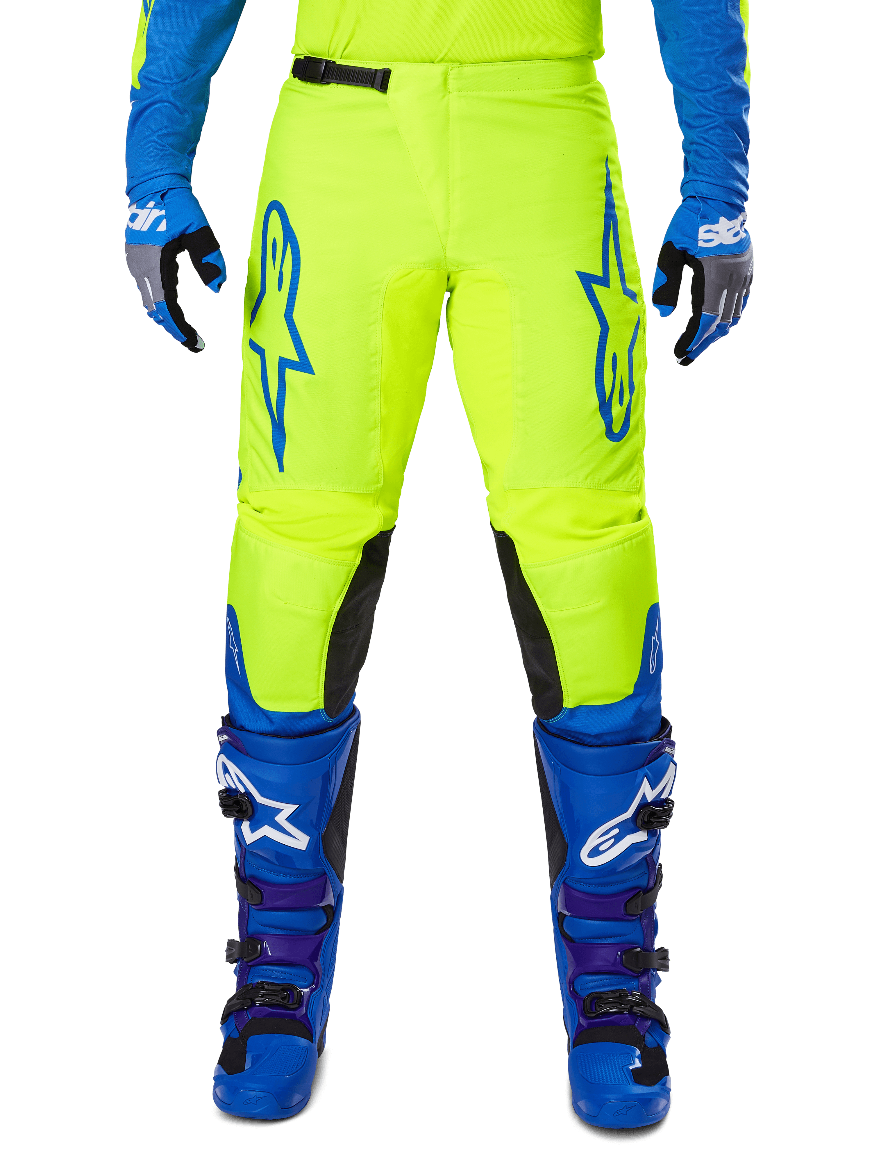 Alpinestars 2025 Fluid Haul Pants, spodnie motocrossowe, jaskrawo żółte i niebieskie, noszone z pasującymi rękawicami i butami, czarne panele wewnętrzne na kolanach, wyrazisty niebieski branding na udach, sportowy ergonomiczny design.