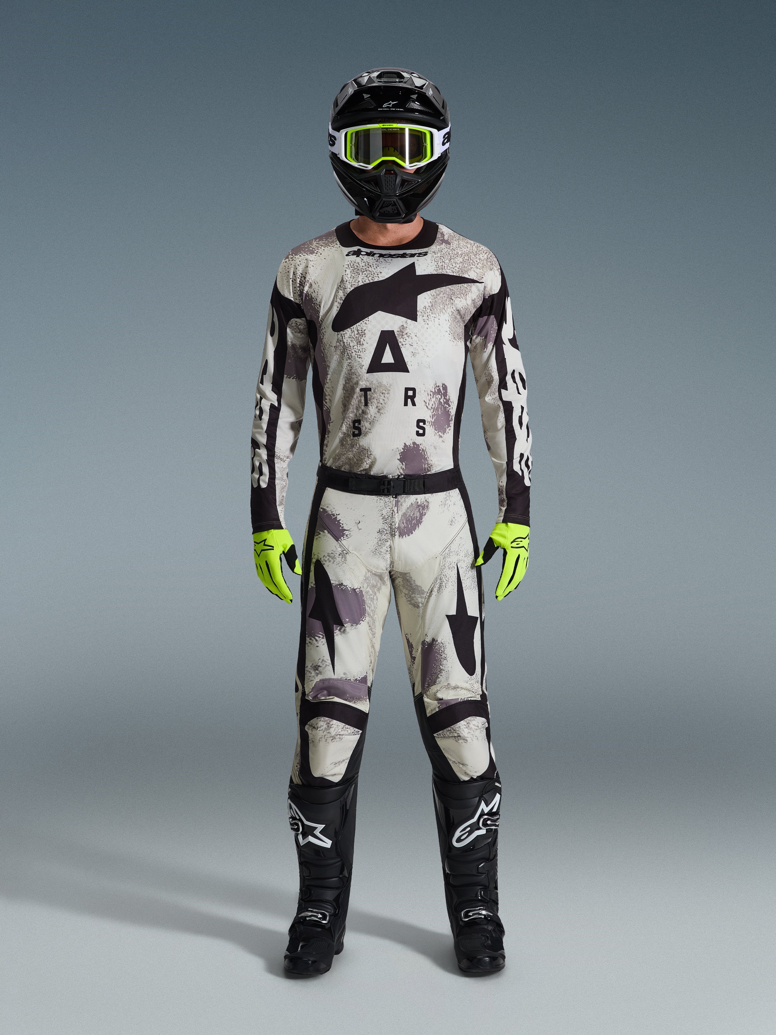 Alpinestars 2026 Racer Lahnd Gear Set, kompletny zestaw motocrossowy, wzór Sand Camo w odcieniach bieli, szarości i czerni, czarny kask z jaskrawozielonymi goglami, neonowe zielone rękawice i czarne buty z białym logo, profesjonalny strój do jazdy off-road