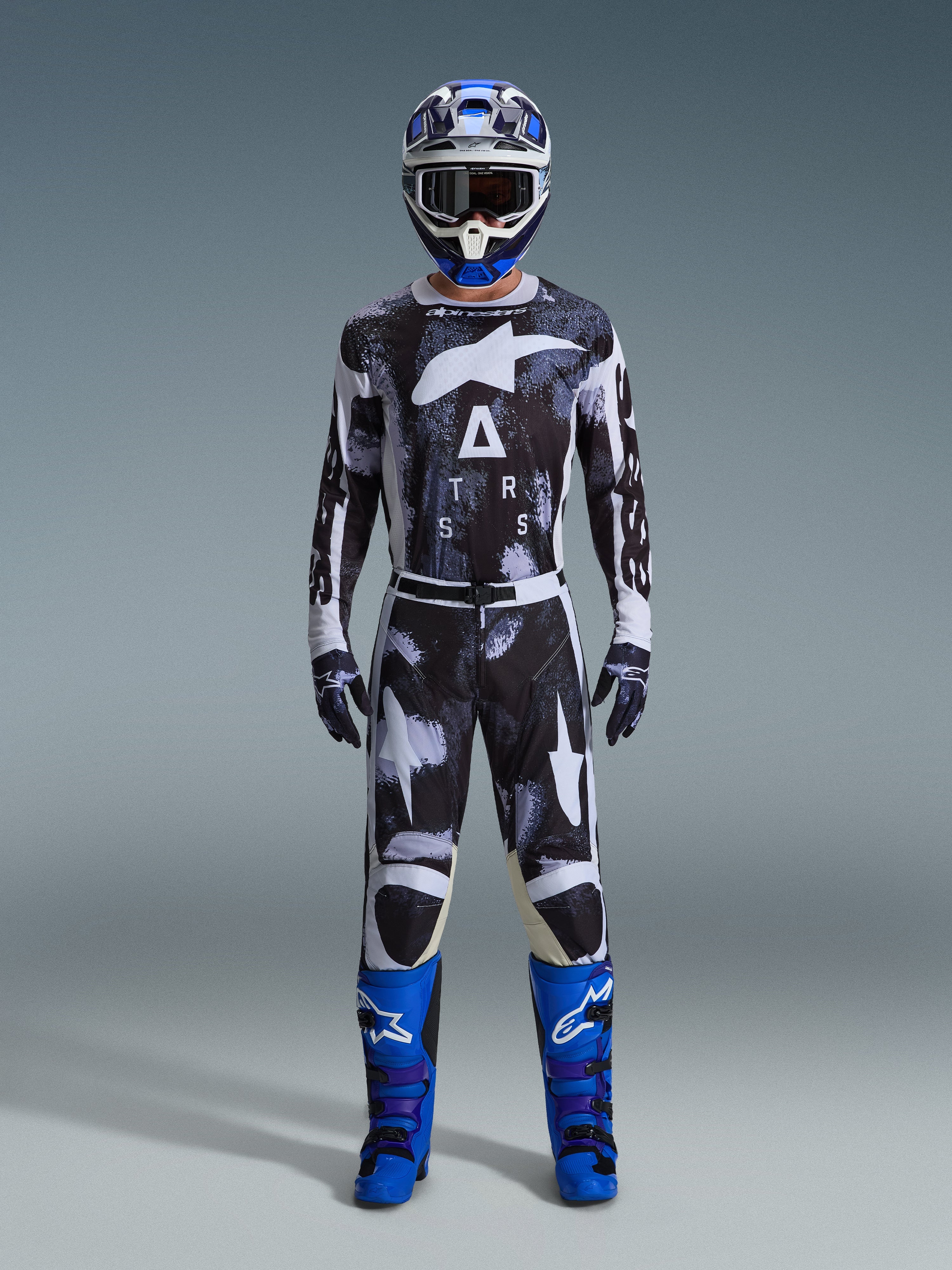 Alpinestars 2026 Racer Lahnd Gear Set, strój motocrossowy, czarno-biały z abstrakcyjnym wzorem Iron Camo, zestawiony z niebiesko-białym kaskiem i jaskrawoniebieskimi butami, kompletny zestaw wyścigowy do jazdy off-road