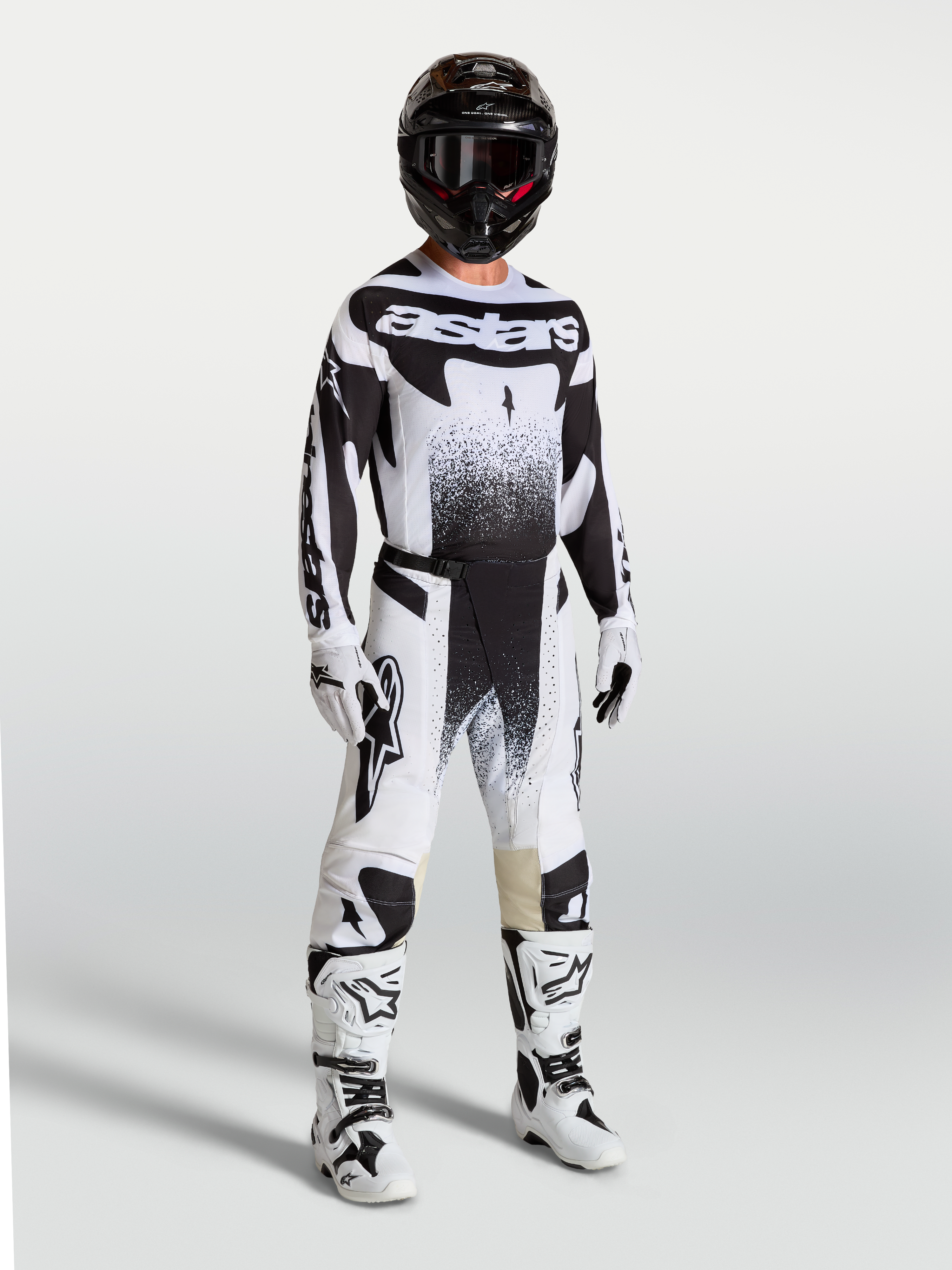 Spodnie Alpinestars Techstar Swan, męskie spodnie motocrossowe, czarne i białe, sportowy krój wyścigowy, elastyczny materiał ripstop, model w pełnym zestawie odzieży wyścigowej z kaskiem i butami.