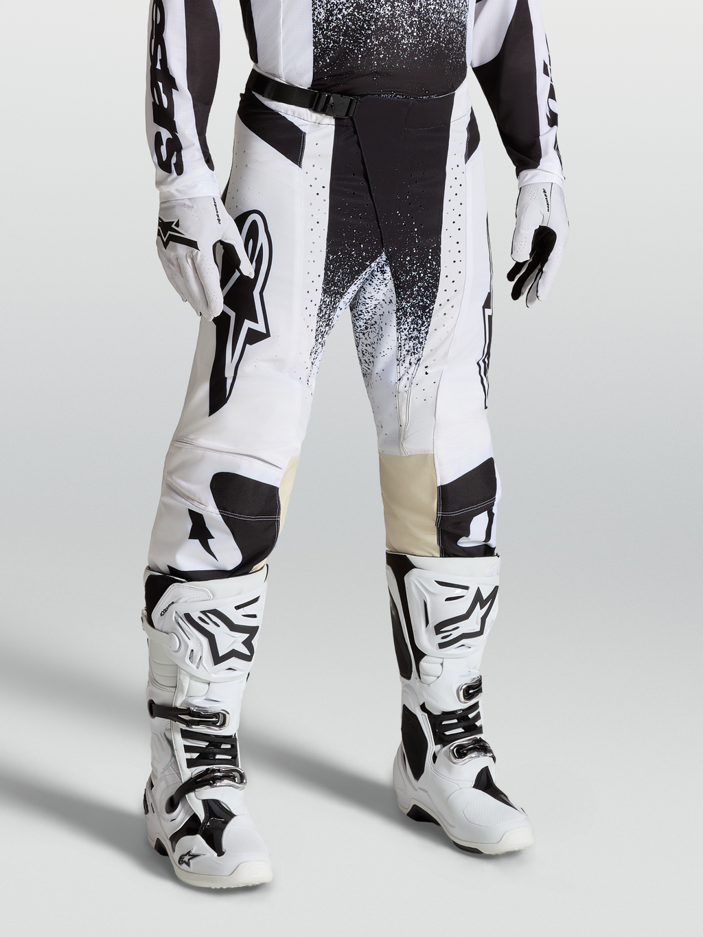 Spodnie Alpinestars Techstar Swan, spodnie motocrossowe na modelu, białe i czarne, sportowy krój wyścigowy z elastycznego materiału ripstop.