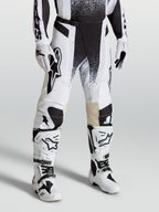 Spodnie Alpinestars Techstar Swan, spodnie motocrossowe na modelu, białe i czarne, sportowy krój wyścigowy z elastycznego materiału ripstop.