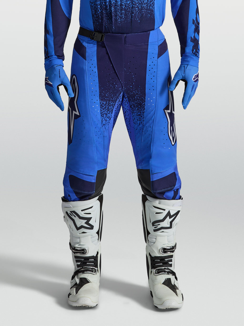 Alpinestars spodnie Techstar Swan, męskie niebieskie spodnie motocrossowe z perforowanymi panelami i białymi butami.