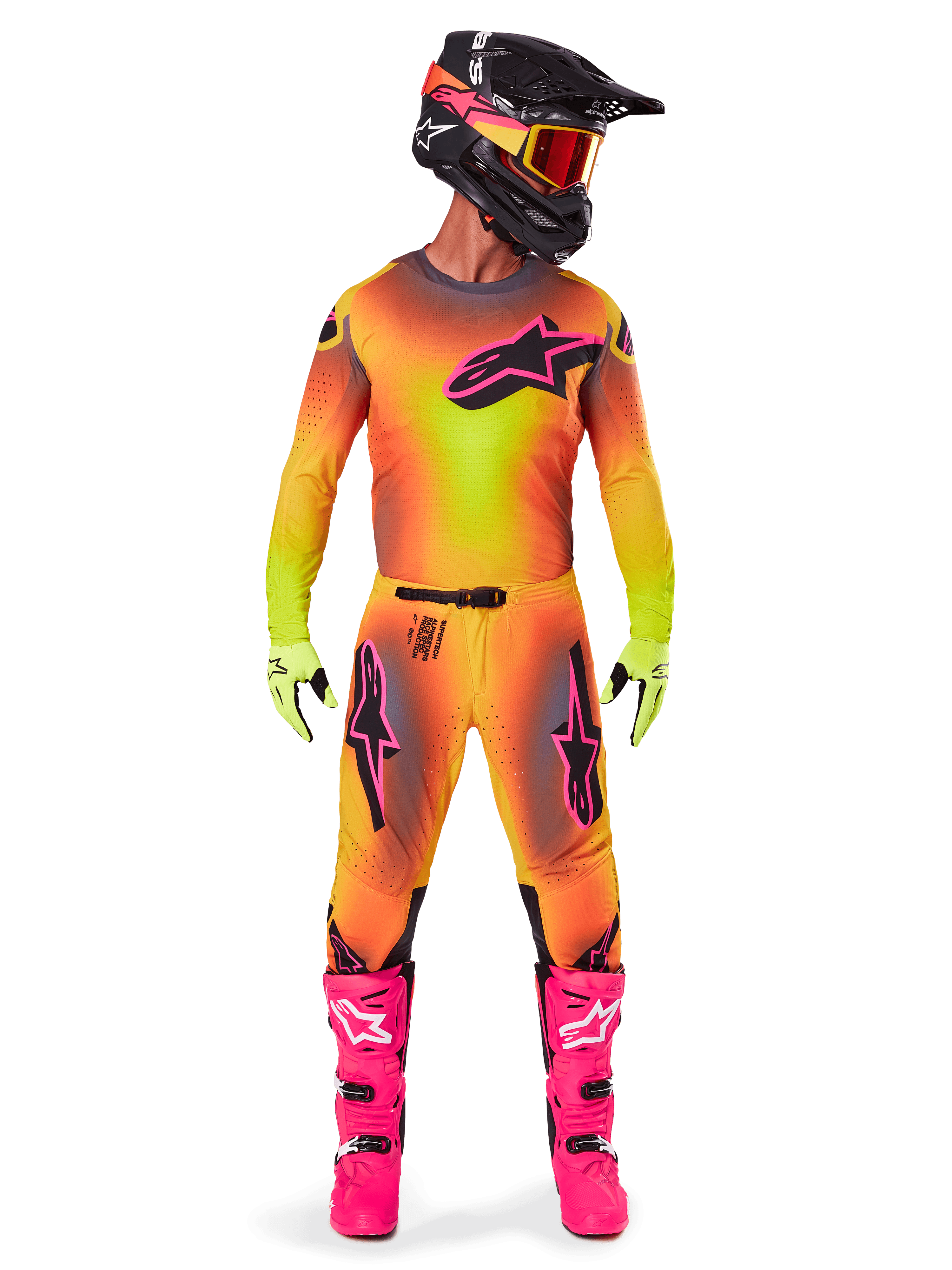Strój motocrossowy Alpinestars 2025 Supertech Lipan, zawodnik w pełnym zestawie, wyrazisty żółto-różowy gradientowy wzór, koszulka z długim rękawem, jaskraworóżowe buty, limonkowe rękawice, czarny kask z pomarańczowymi goglami