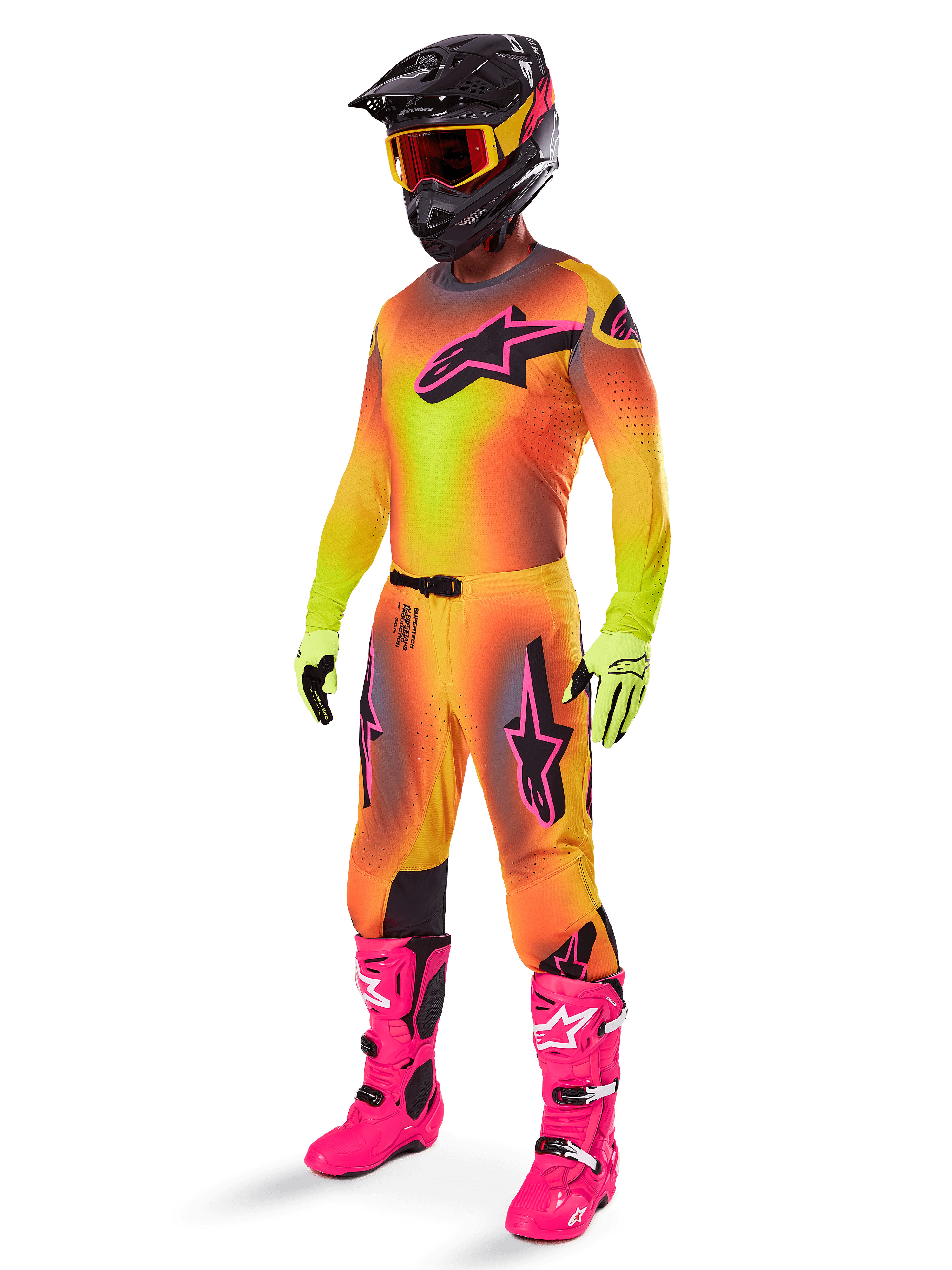 Alpinestars Supertech Lipan Pants 2025, spodnie motocrossowe, żółto-różowe, noszone jako część pełnego zestawu z dopasowaną koszulką z gradientem, jaskraworóżowymi butami, żółtymi rękawicami i czarnym kaskiem, z wyraźnymi czarnymi logotypami i sportowym krojem do wyścigów off-road