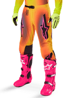 Alpinestars 2025 Supertech Lipan Gear Set, spodnie motocrossowe, żółto-pomarańczowy gradient z różowymi i fioletowymi akcentami, czarne logo Alpinestars na udach, żółte rękawice i jaskraworóżowe buty motocrossowe