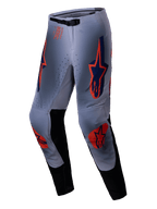 Alpinestars 2025 Supertech Lipan Pants, spodnie motocrossowe, szaro-pomarańczowe fluo, z wyrazistymi pomarańczowymi i granatowymi logo gwiazdy na udach i kolanach, czarne panele po wewnętrznej stronie nogawek i regulowany pas, zaprojektowane dla profesjonalnych osiągów w terenie