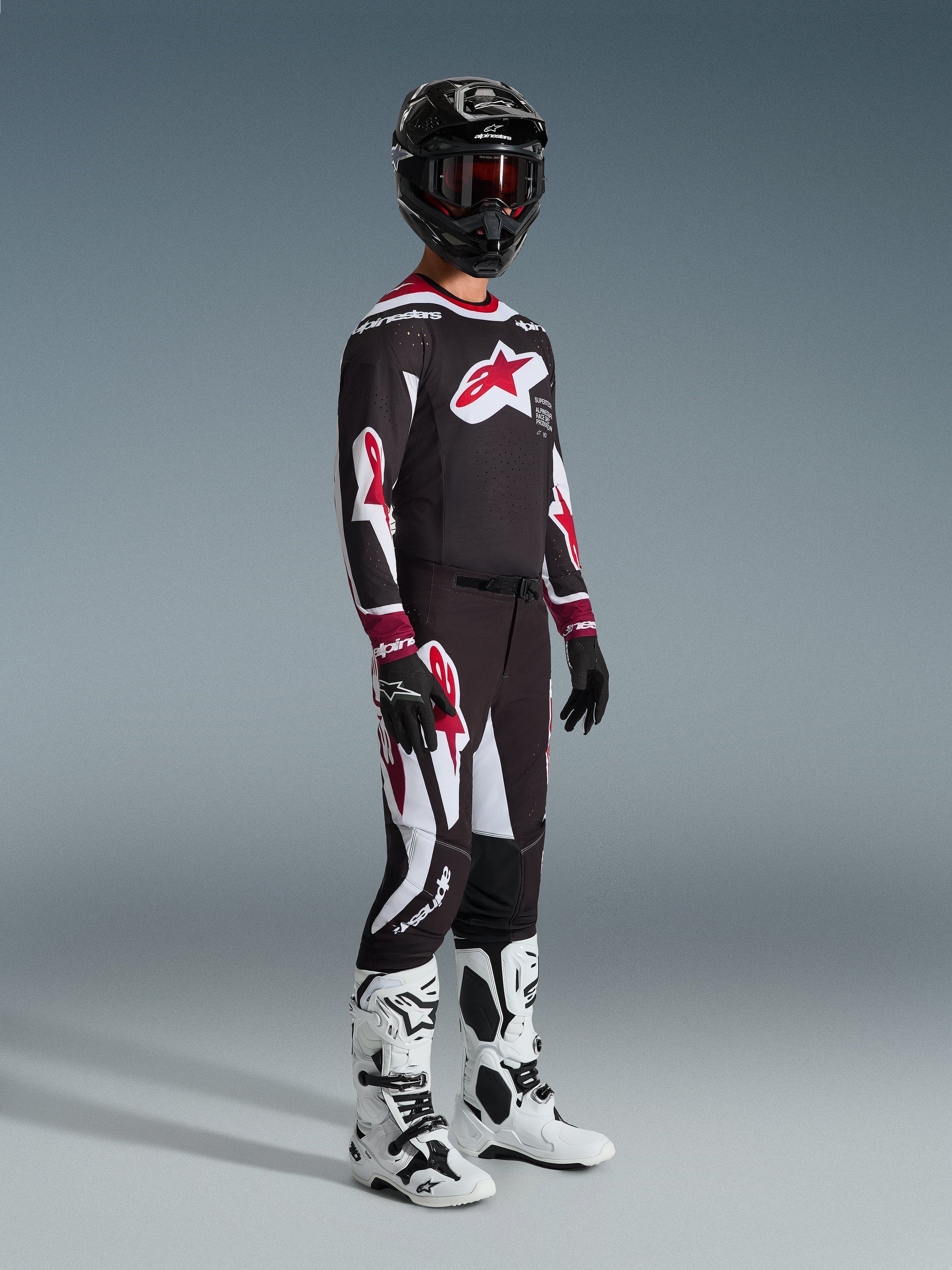 Alpinestars 2026 Supertech AFD Vista Pants, spodnie motocrossowe, czarno-czerwono-białe, noszone z pasującą bluzą wyścigową, czarnym kaskiem z czerwonymi goglami, czarnymi rękawicami i białymi butami, sportowa odzież wyczynowa do jazdy off-road