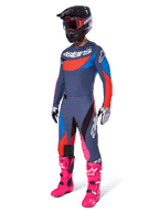 Alpinestars 2025 Techstar Dreem Pants, spodnie motocrossowe, szary wielokolorowy z niebieskimi, czerwonymi i różowymi akcentami, noszone z pasującą koszulką i jaskraworóżowymi butami, czarnym kaskiem i białymi rękawicami, kompletny zestaw odzieży do wyścigów terenowych