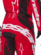 Alpinestars Techstar Dreem Pants 2025, spodnie motocrossowe, jaskrawoczerwone i czarne, zbliżenie na tylną część pasa i siedzenia, wyraźny biały branding Alpinestars, czarne elastyczne panele, techniczny tekst na pasku, zaprojektowane pod kątem wydajności w wyścigach terenowych.