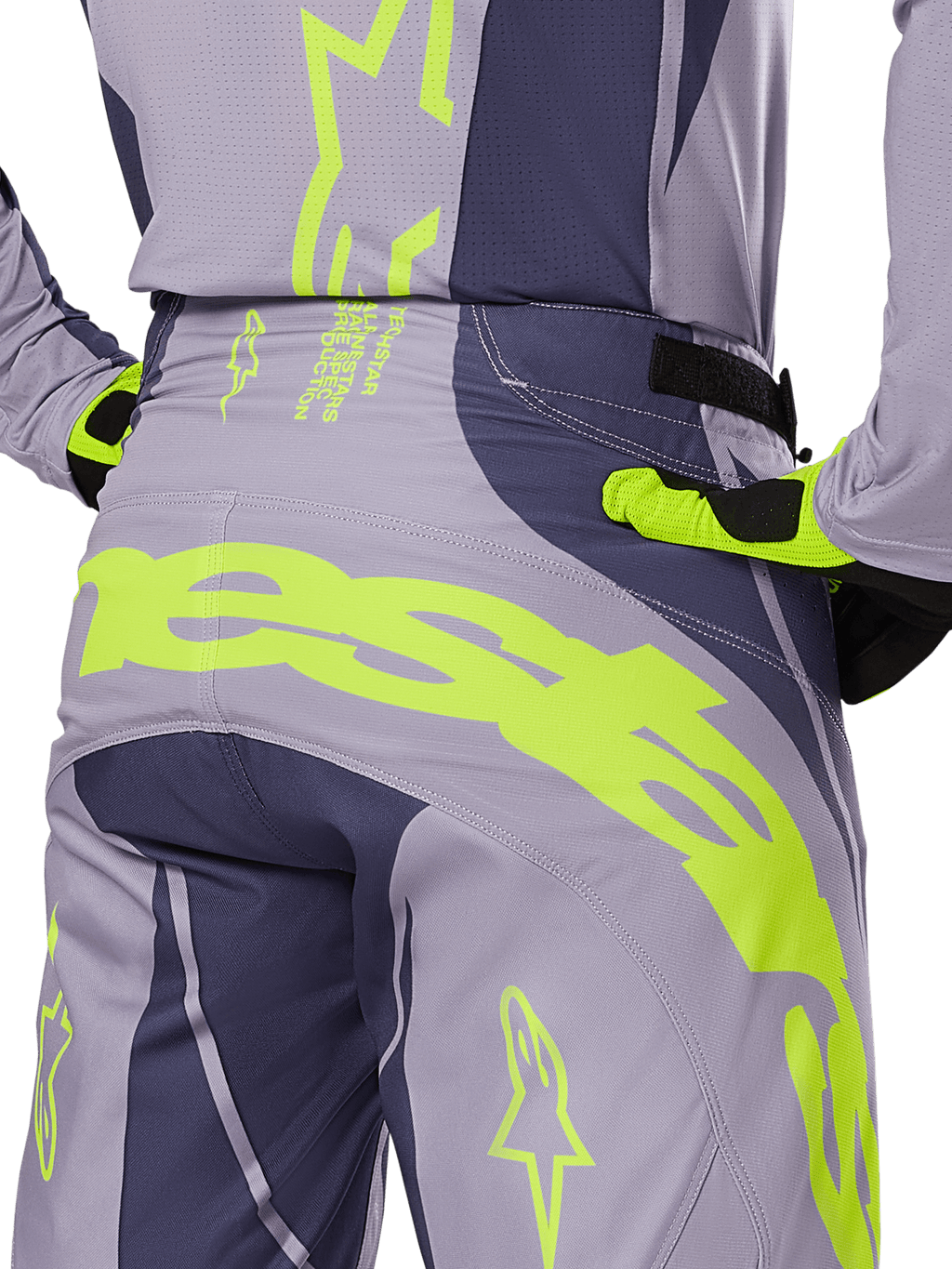 Spodnie Alpinestars Techstar Dreem 2025, spodnie motocrossowe, szare i ciemnoszare z neonowymi żółtymi akcentami, widok z tyłu prezentujący wyraźne logo Alpinestars na karczku, noszone z pasującą koszulką i rękawicami, zaprojektowane do wyścigów terenowych