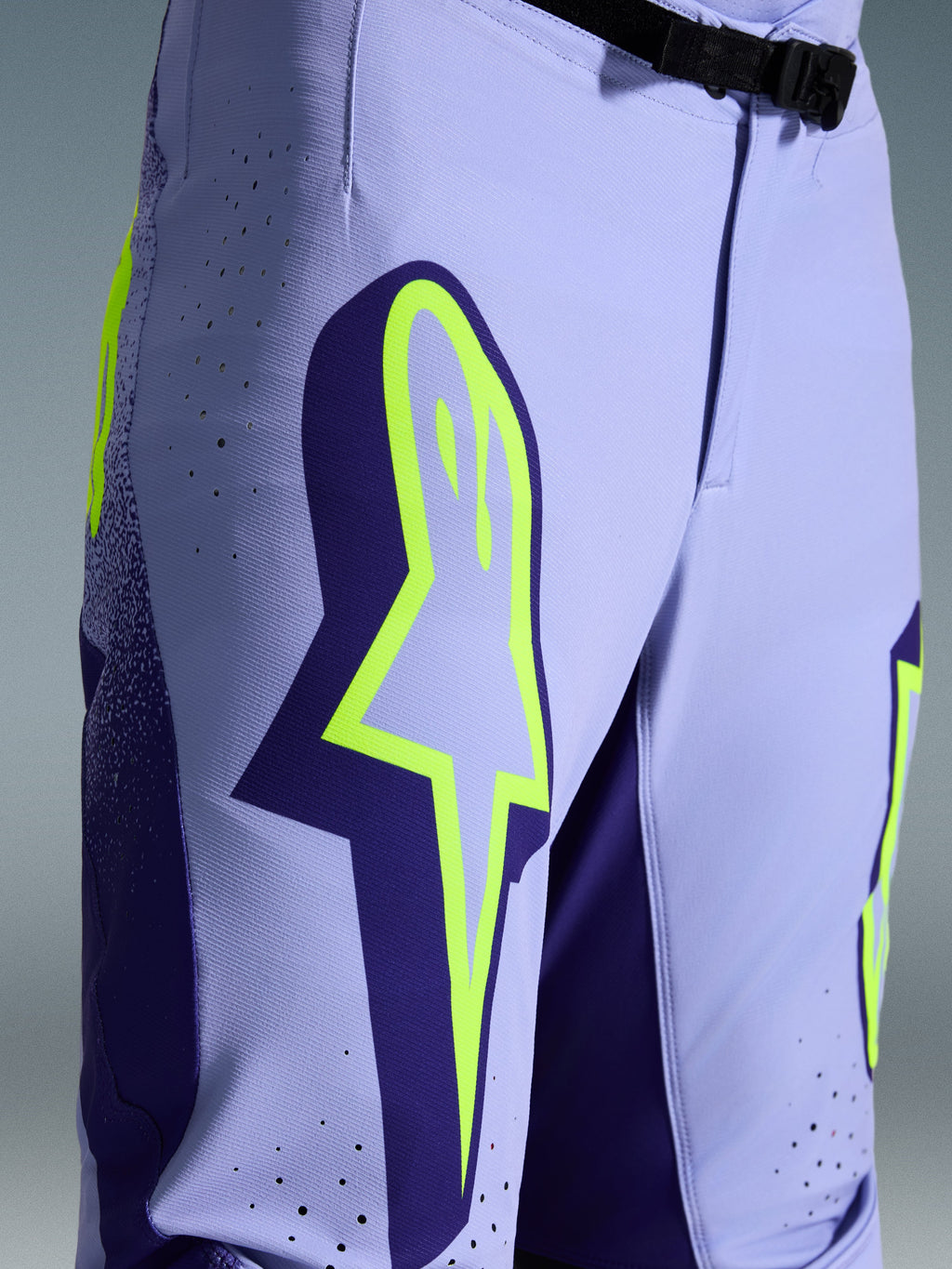 Alpinestars 2026 Supertech Scenz Pants, spodnie motocrossowe, fioletowo-żółty fluo, zbliżenie na duże żółte logo na udzie, laserowo wycinane perforacje wentylacyjne i magnetyczna klamra w pasie, sportowy krój off-road