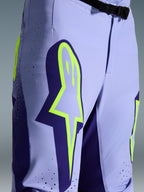 Alpinestars 2026 Supertech Scenz Pants, spodnie motocrossowe, fioletowo-żółty fluo, zbliżenie na duże żółte logo na udzie, laserowo wycinane perforacje wentylacyjne i magnetyczna klamra w pasie, sportowy krój off-road