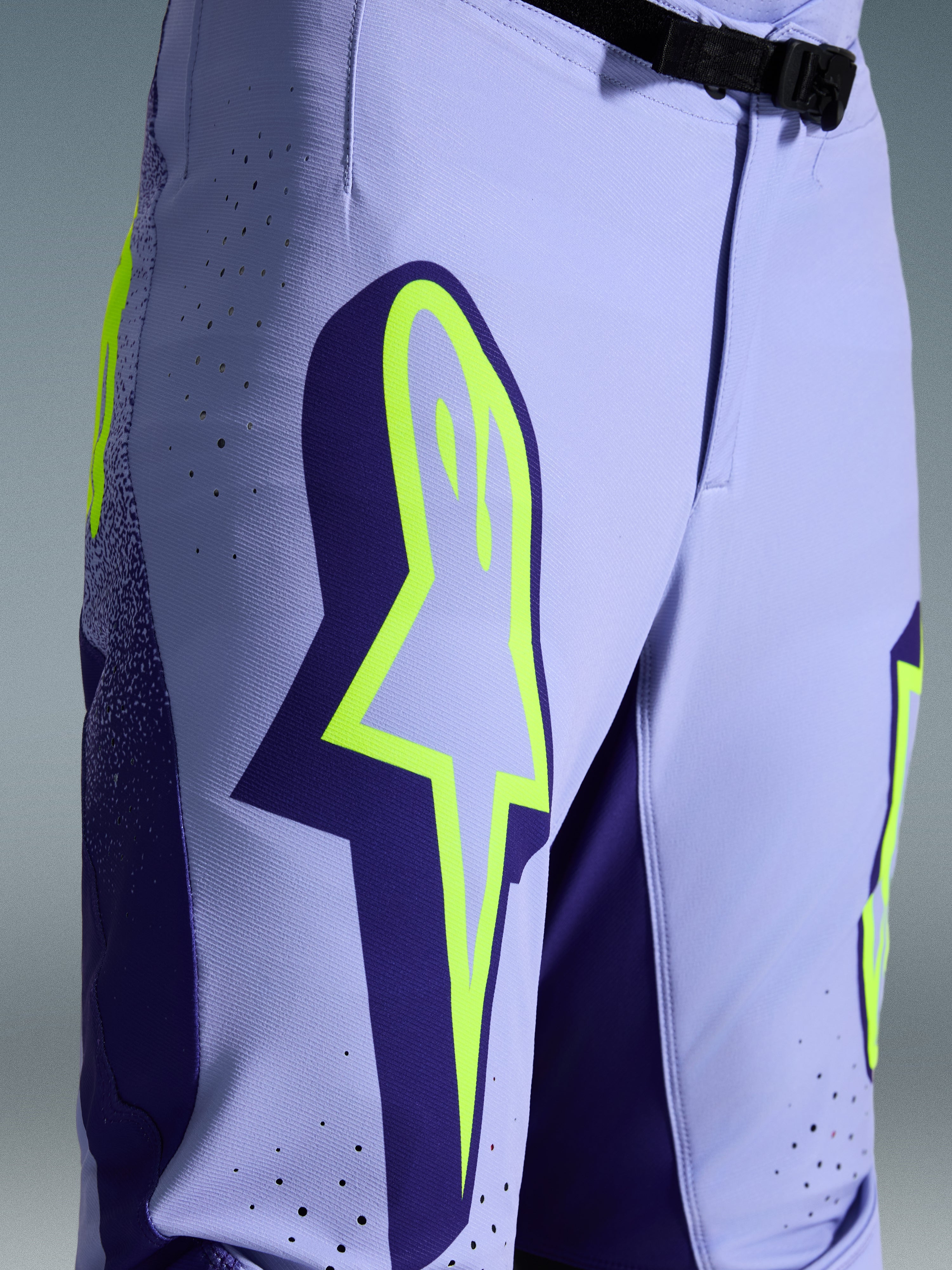 Alpinestars 2026 Supertech Scenz Pants, spodnie motocrossowe, fioletowo-żółty fluo, zbliżenie na duże żółte logo na udzie, laserowo wycinane perforacje wentylacyjne i magnetyczna klamra w pasie, sportowy krój off-road