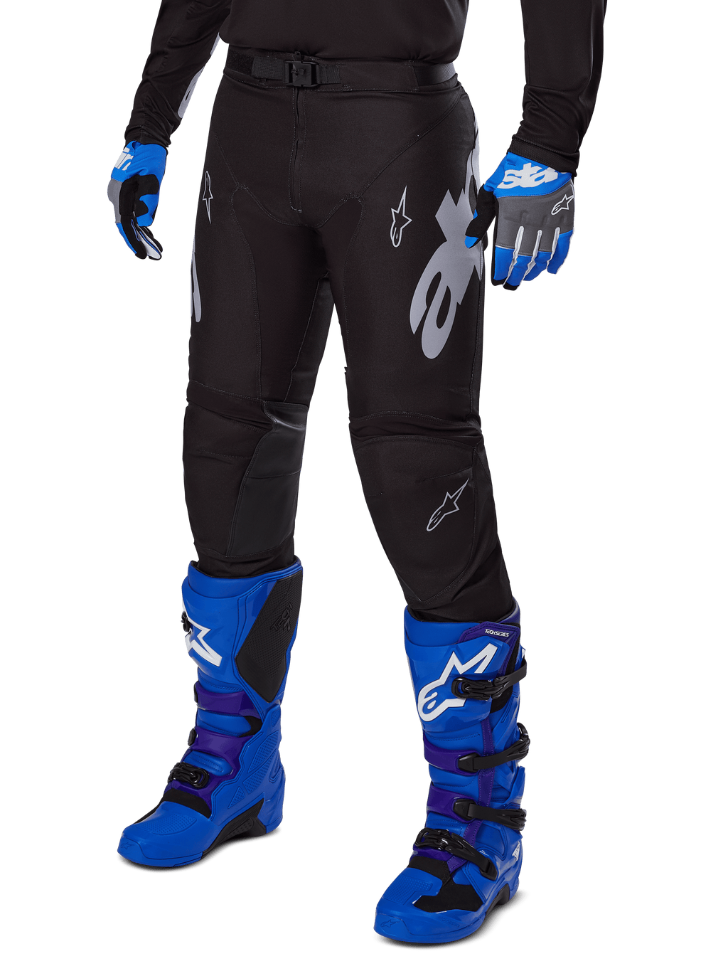 Alpinestars 2025 Racer Graphite Pants, czarne spodnie motocrossowe z białymi i szarymi grafikami, noszone z jasnoniebieskimi butami motocrossowymi i pasującymi niebieskimi rękawicami, wytrzymała tkanina techniczna do jazdy terenowej