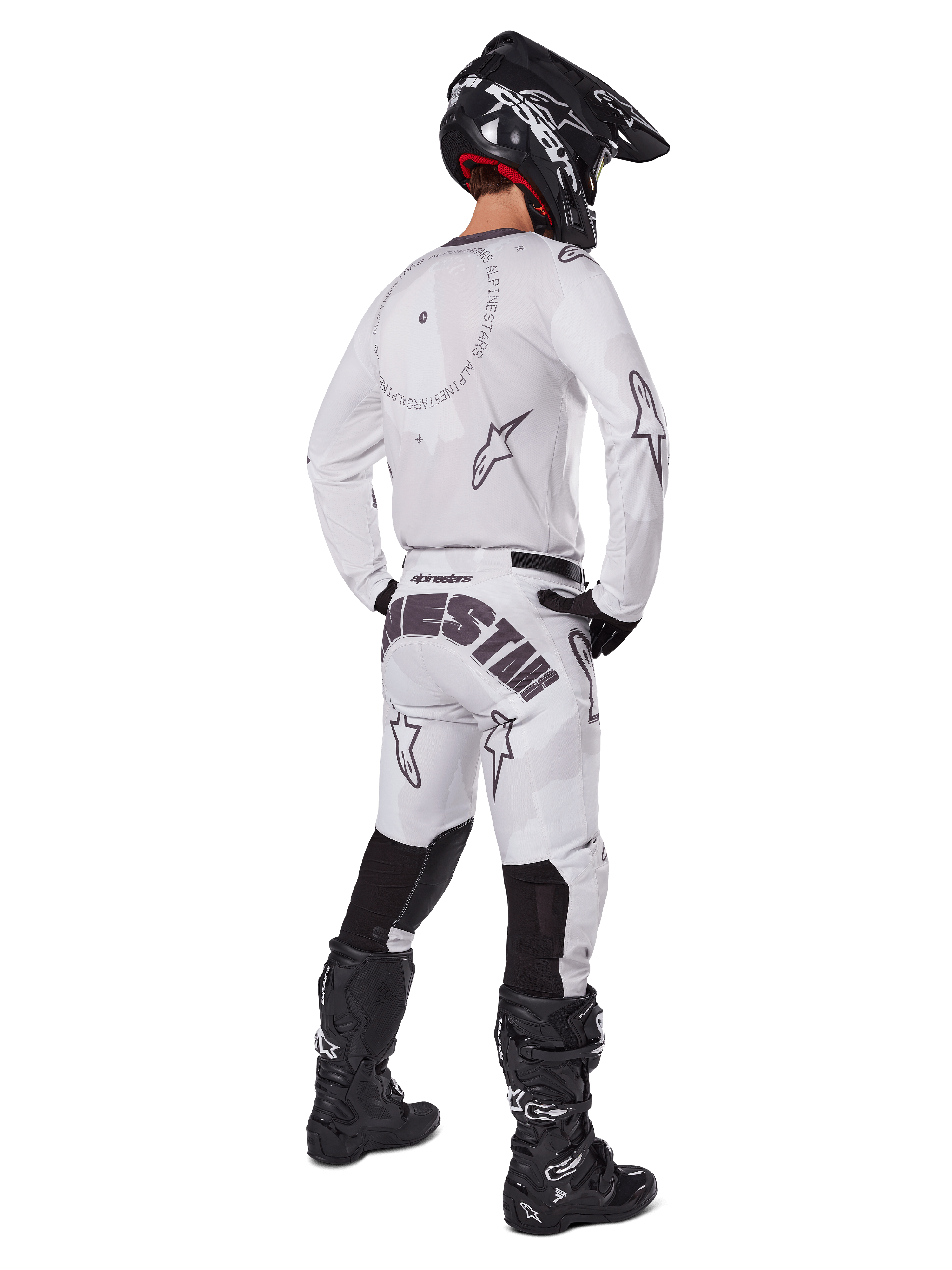 Alpinestars 2025 Racer Hollow Pants, spodnie motocrossowe, jasny brąz camo i biały, widok z tyłu pokazujący wyraźne czarne napisy na siedzeniu i logo gwiazdy, zestawione z pasującą koszulką, czarnymi butami i czarnym kaskiem dla pełnego off-roadowego wyglądu