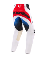 Alpinestars 2026 Techstar Knif Pants, spodnie motocrossowe, biało-czerwono-niebieskie, widok z tyłu z dużym czarnym logo Alpinestars na czerwonym panelu siedziska, niebieskie gradientowe akcenty na udach, beżowe skórzane panele po wewnętrznej stronie kolan, sportowy krój wyścigowy.