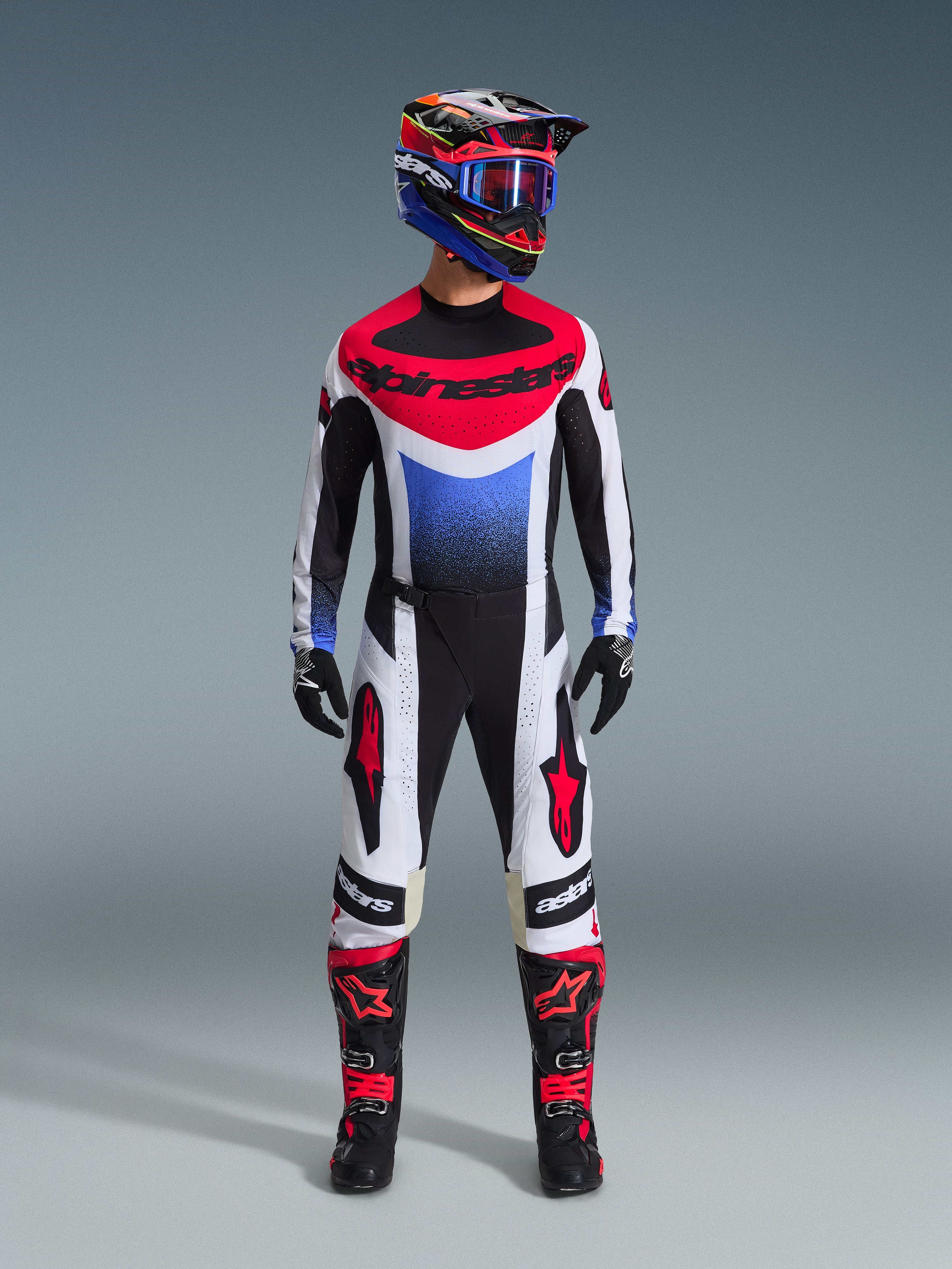 Zestaw Techstar Knif 2026, strój motocrossowy, czerwono-biało-niebieska koszulka z logo Alpinestars, pasujące biało-czarne spodnie z czerwonymi detalami, kolorowy kask wyścigowy z niebieskimi goglami, czarne buty z czerwonymi akcentami, kompletny zestaw wyścigowy MX