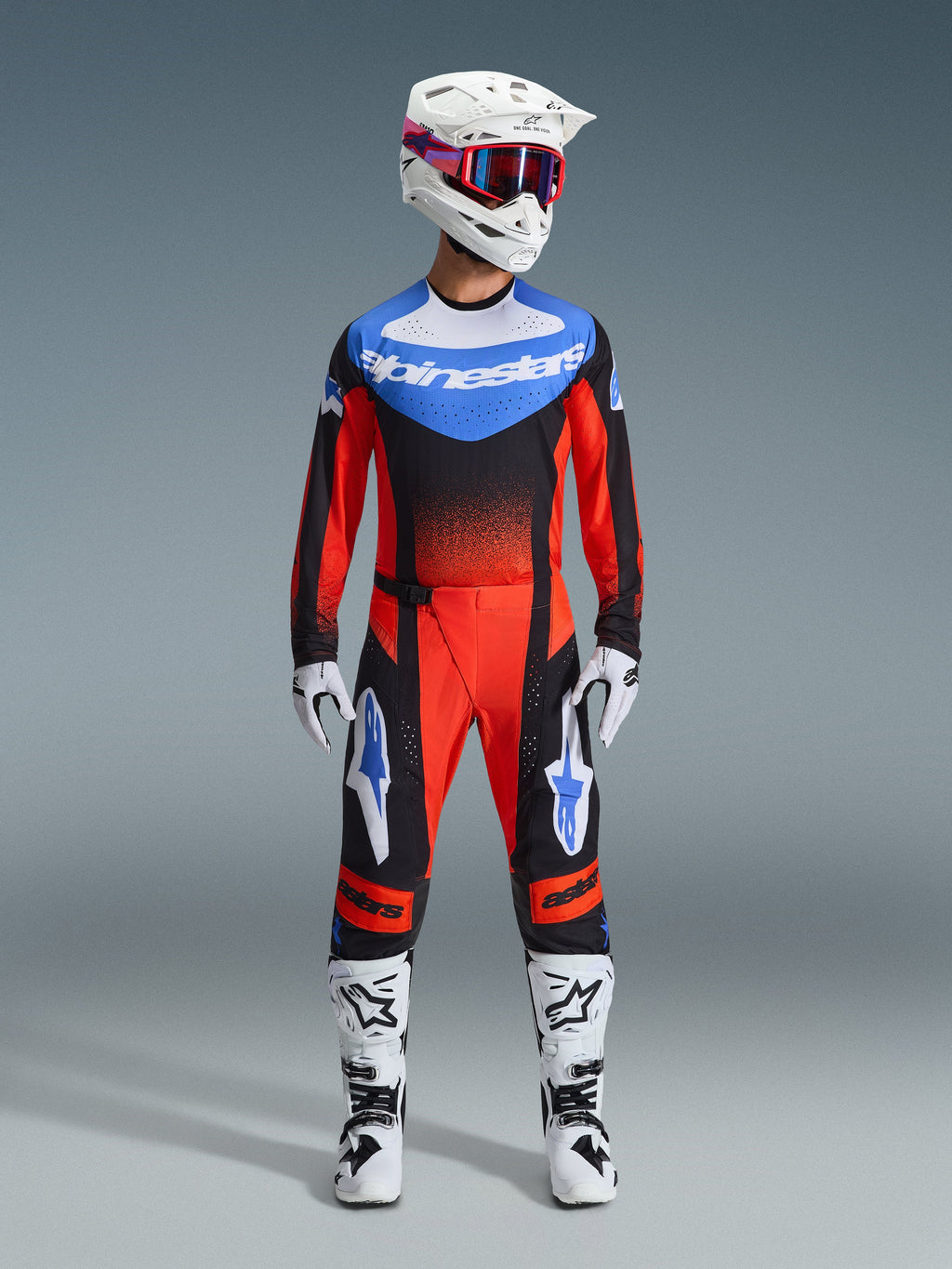 Alpinestars 2026 Techstar Knif Gear Set, odzież motocrossowa, czerwony i czarny z niebieskimi akcentami, kompletny strój MX zawierający koszulkę, spodnie, biały kask z różową i niebieską grafiką, białe rękawice i białe buty, profesjonalny sprzęt do wyścigów terenowych