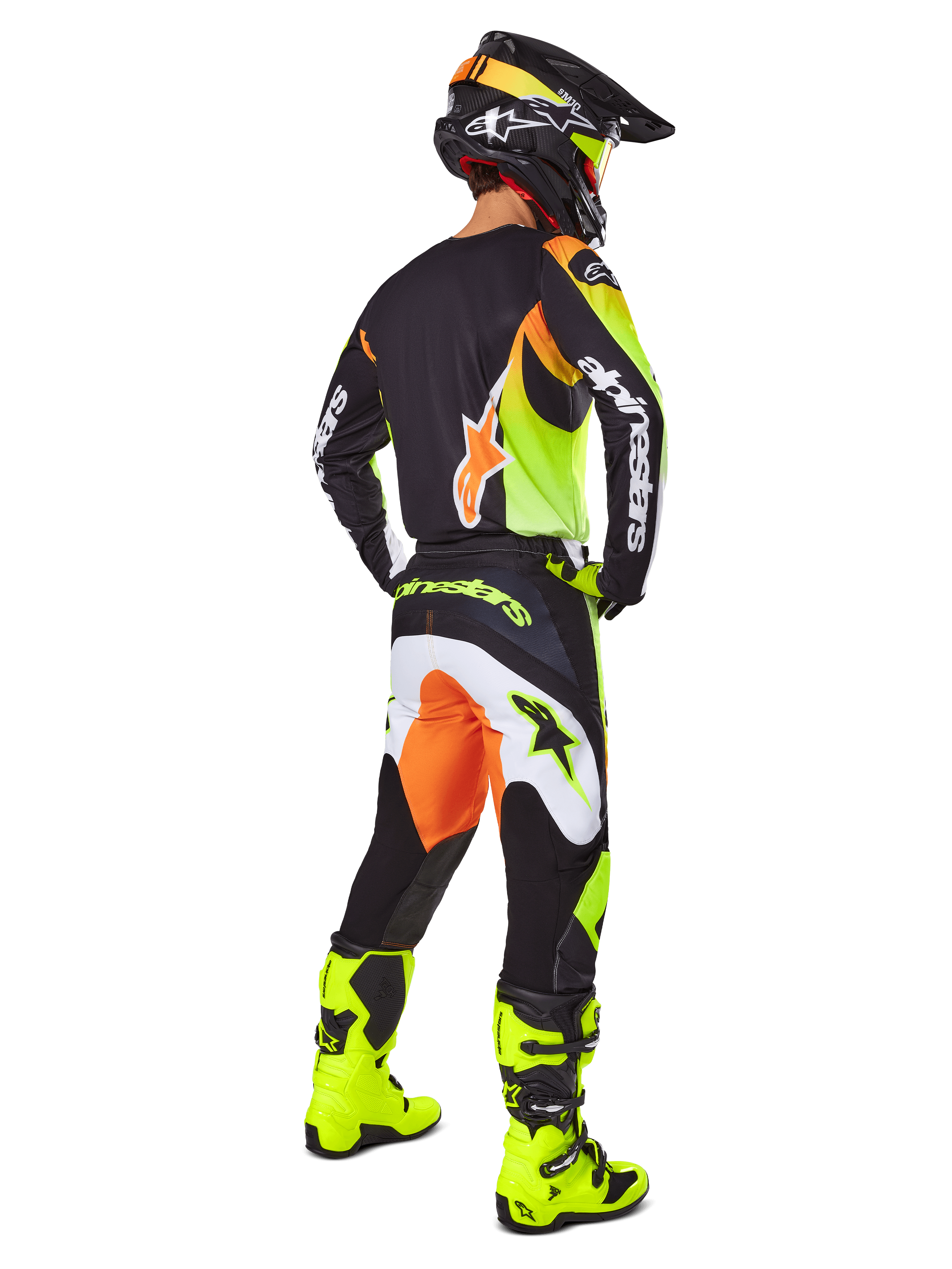 Jeździec motocrossowy widziany z tyłu w zestawie Alpinestars 2025 Fluid Wurx, czarna koszulka z żółtymi i pomarańczowymi akcentami, pasujące czarne spodnie z białymi i pomarańczowymi panelami, jaskrawożółte buty i czarny kask, kompletny strój wyścigowy off-road