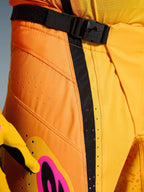 Alpinestars 2026 Techstar Nomur Pants, spodnie motocrossowe, pomarańczowo-żółto-różowe, zbliżenie na okolicę pasa z magnetycznym zapięciem na klamrę SX2, czarnym paskiem regulacyjnym i laserowo wycinanymi perforacjami wentylacyjnymi na wytrzymałym materiale ripstop