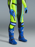Alpinestars Techstar Nomur 2026, spodnie motocrossowe, żółty fluo, ciemnogranatowy i niebieski UCLA, zestawione z pasującymi niebieskimi butami i rękawicami, z wyraźnymi białymi logo i wzmocnionymi panelami, profesjonalny strój do wyścigów terenowych