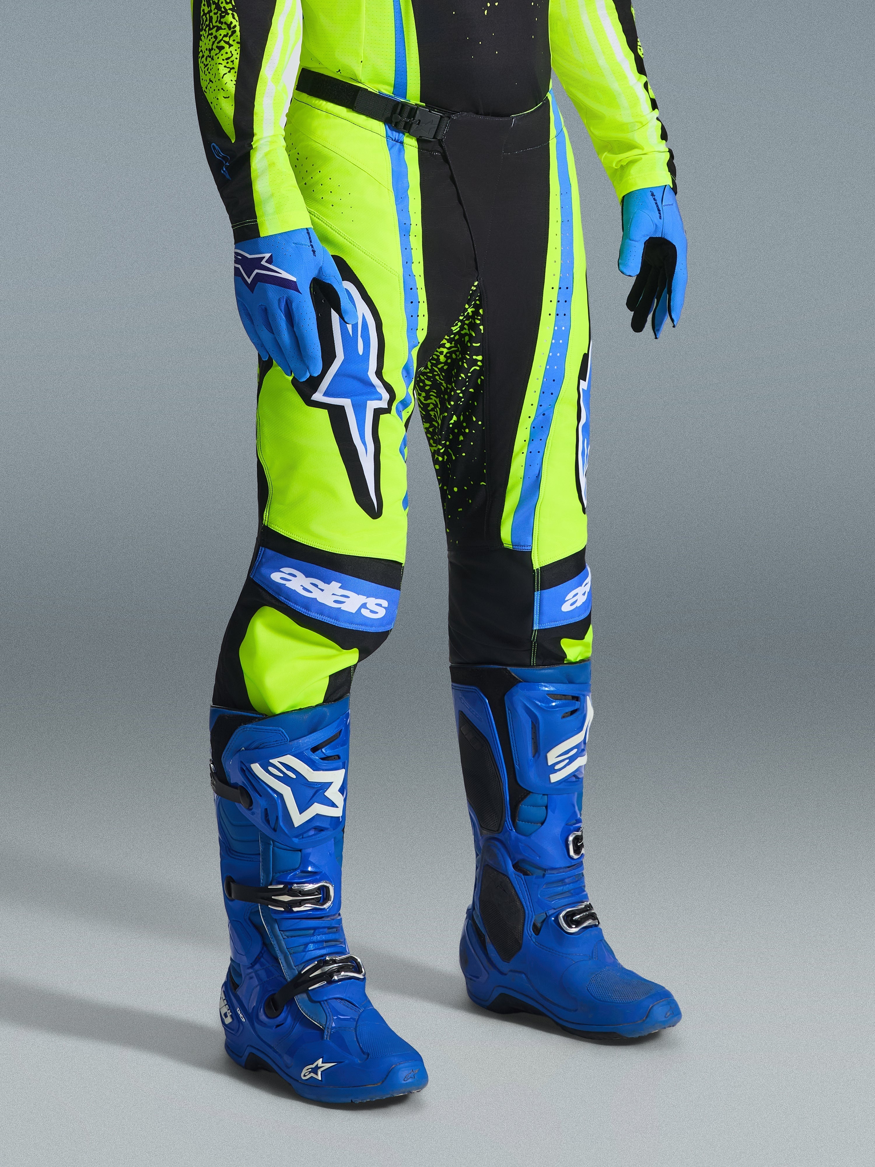 Alpinestars Techstar Nomur 2026, spodnie motocrossowe, żółty fluo, ciemnogranatowy i niebieski UCLA, zestawione z pasującymi niebieskimi butami i rękawicami, z wyraźnymi białymi logo i wzmocnionymi panelami, profesjonalny strój do wyścigów terenowych