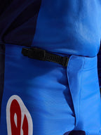 Alpinestars 2026 Fluid Grid Pants, spodnie motocrossowe, niebiesko-czerwone, zbliżenie na czarny system zapięcia zapadkowego w pasie, wytrzymały niebieski materiał poliestrowy z czerwono-białym akcentem logo, zaprojektowane dla wydajności off-road
