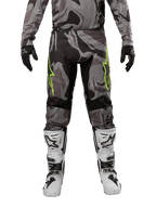 Spodnie Alpinestars 2024 Racer Tactical, spodnie motocrossowe, szary kamuflaż Cast Gray Camo Magnet, zestawione z pasującą bluzą, czarnymi rękawicami oraz biało-czarnymi butami, z limonkowymi logotypami gwiazdy na udach i czarnymi elastycznymi panelami, widok z przodu odzieży do jazdy terenowej