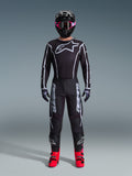 Zestaw Alpinestars 2026 Fluid Apex, strój motocrossowy, czarny z szarymi akcentami, koszulka z dużym białym logo Astars, pasujące spodnie z wyraźnym brandingiem, czarny kask z różowymi goglami, jaskrawoczerwone buty, kompletny zestaw do wyścigów off-road