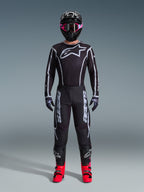 Zestaw Alpinestars 2026 Fluid Apex, strój motocrossowy, czarny z szarymi akcentami, koszulka z dużym białym logo Astars, pasujące spodnie z wyraźnym brandingiem, czarny kask z różowymi goglami, jaskrawoczerwone buty, kompletny zestaw do wyścigów off-road