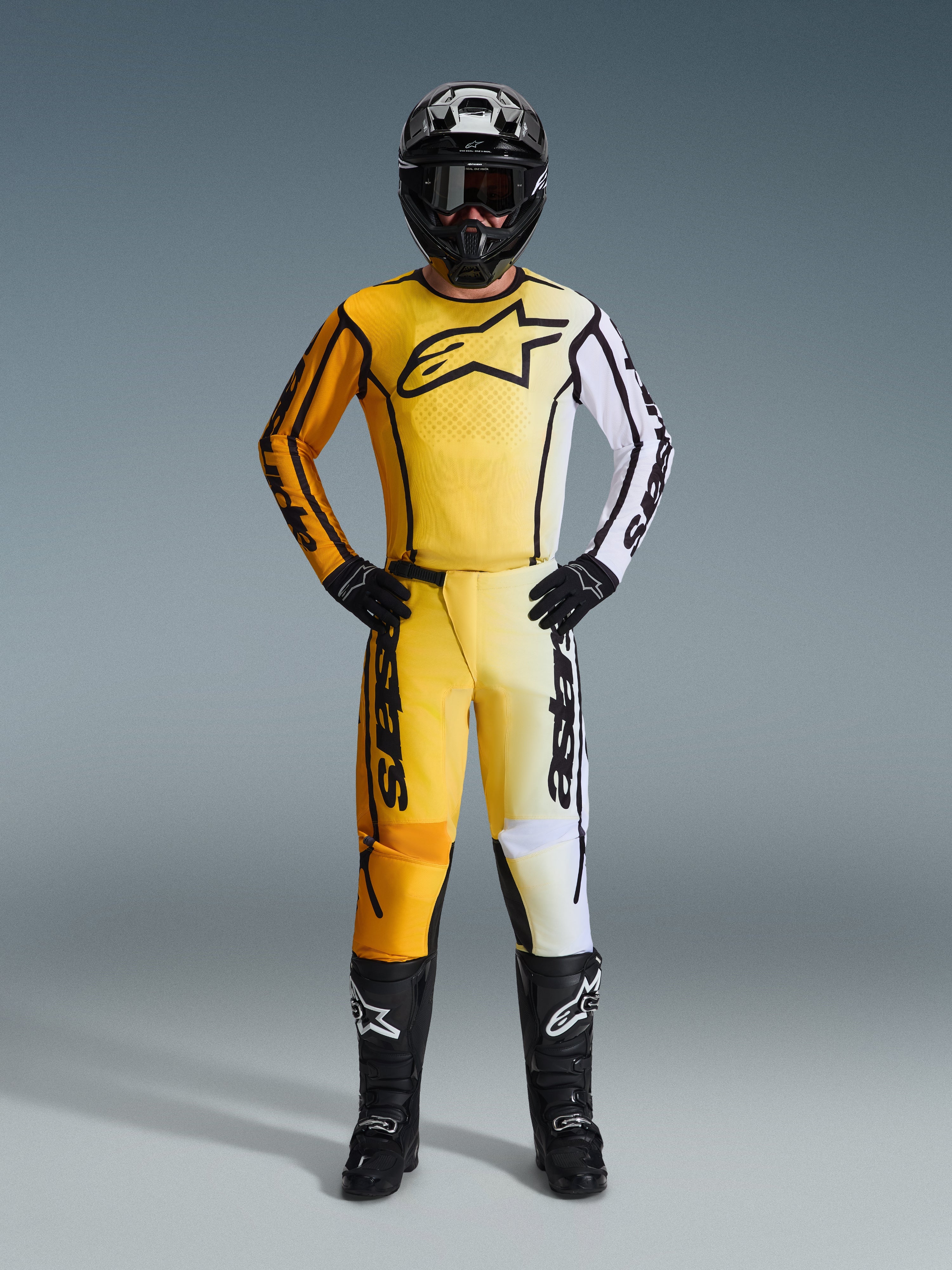 Alpinestars 2026 Fluid Apex Gear Set, Full Motocross suit featuring a yellow orange and white gradient jersey and pants, styled with a black helmet goggles and boots, bold black logo on chest, complete off-road racing protection
