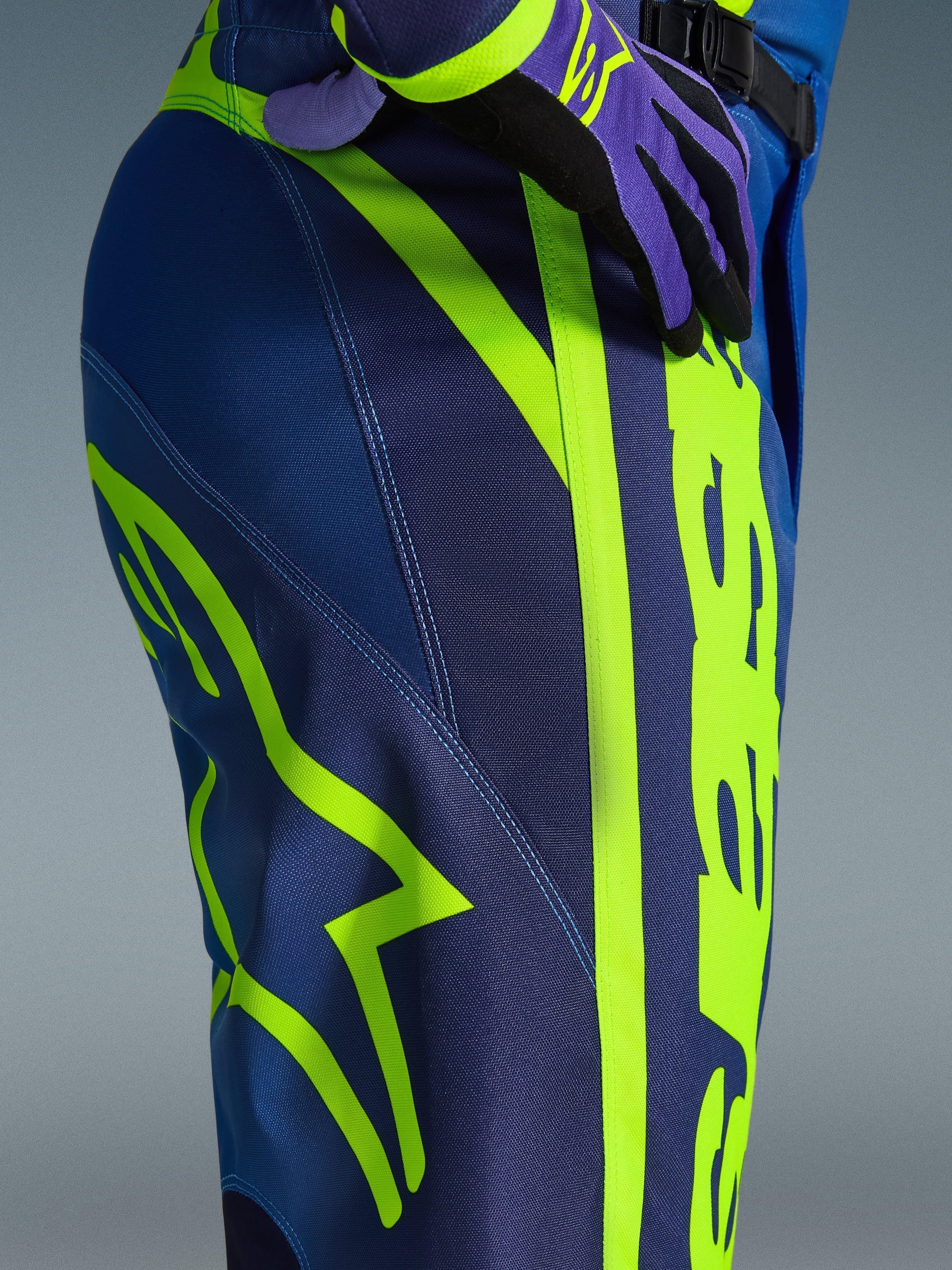 Alpinestars 2026 Fluid Apex Pants, spodnie motocrossowe, niebieskie i neonowożółte, zbliżenie na bok i biodro z wyraźnym neonowożółtym brandingiem Alpinestars, wytrzymały materiał poliestrowy do jazdy off-road, część pasującego zestawu odzieży