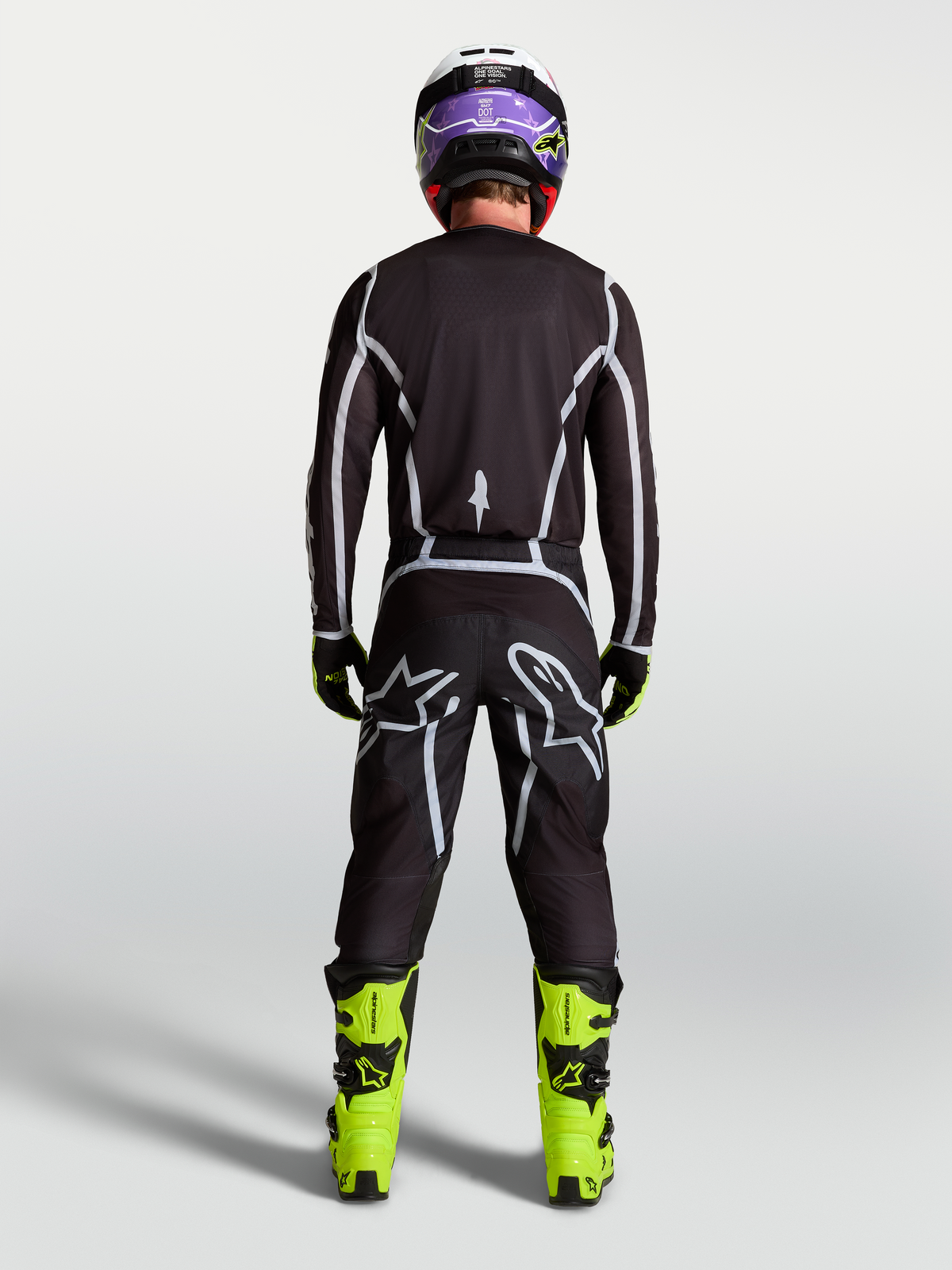 Spodnie Alpinestars Fluid Apex V2, męskie spodnie motocrossowe, czarne i srebrne, widok z tyłu na motocykliście, ergonomiczny sportowy krój.