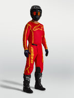 Spodnie Alpinestars Fluid Apex V2, męskie spodnie motocrossowe, czerwone i złote, na modelu w pełnym zestawie off-road.