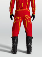 Alpinestars spodnie Fluid Apex V2, męskie spodnie motocrossowe, czerwone i złote, widok z tyłu, czarne buty.