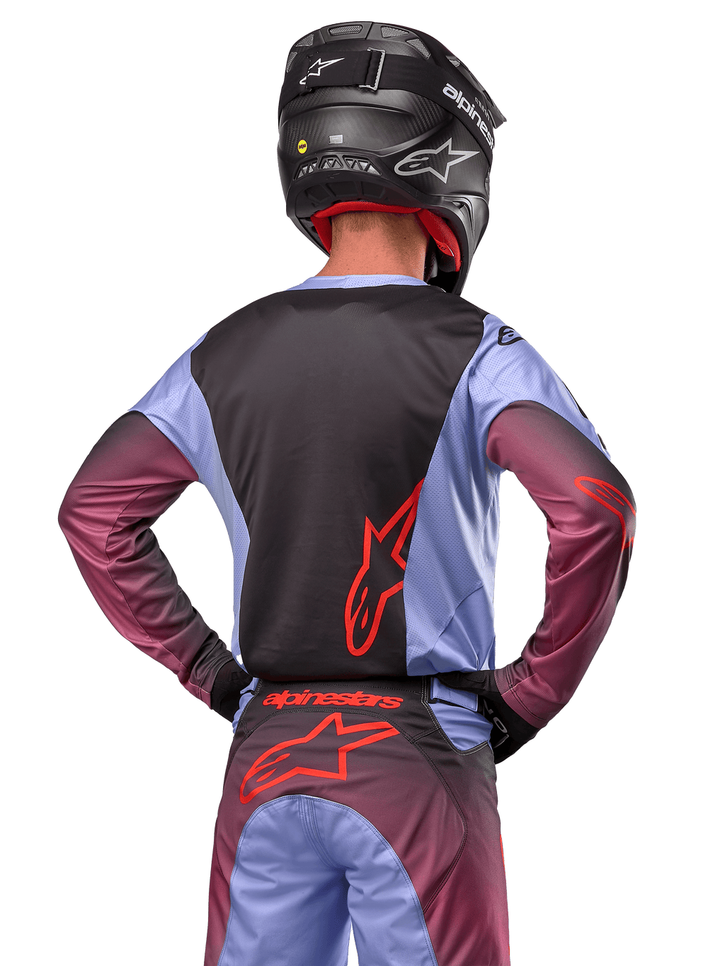Zawodnik motocrossowy od tyłu w stroju Alpinestars 2024 Racer Hoen, fioletowo-czarna koszulka z czerwonym logo, pasujące spodnie z czerwonymi akcentami, czarny kask, dopasowany strój do wyścigów terenowych