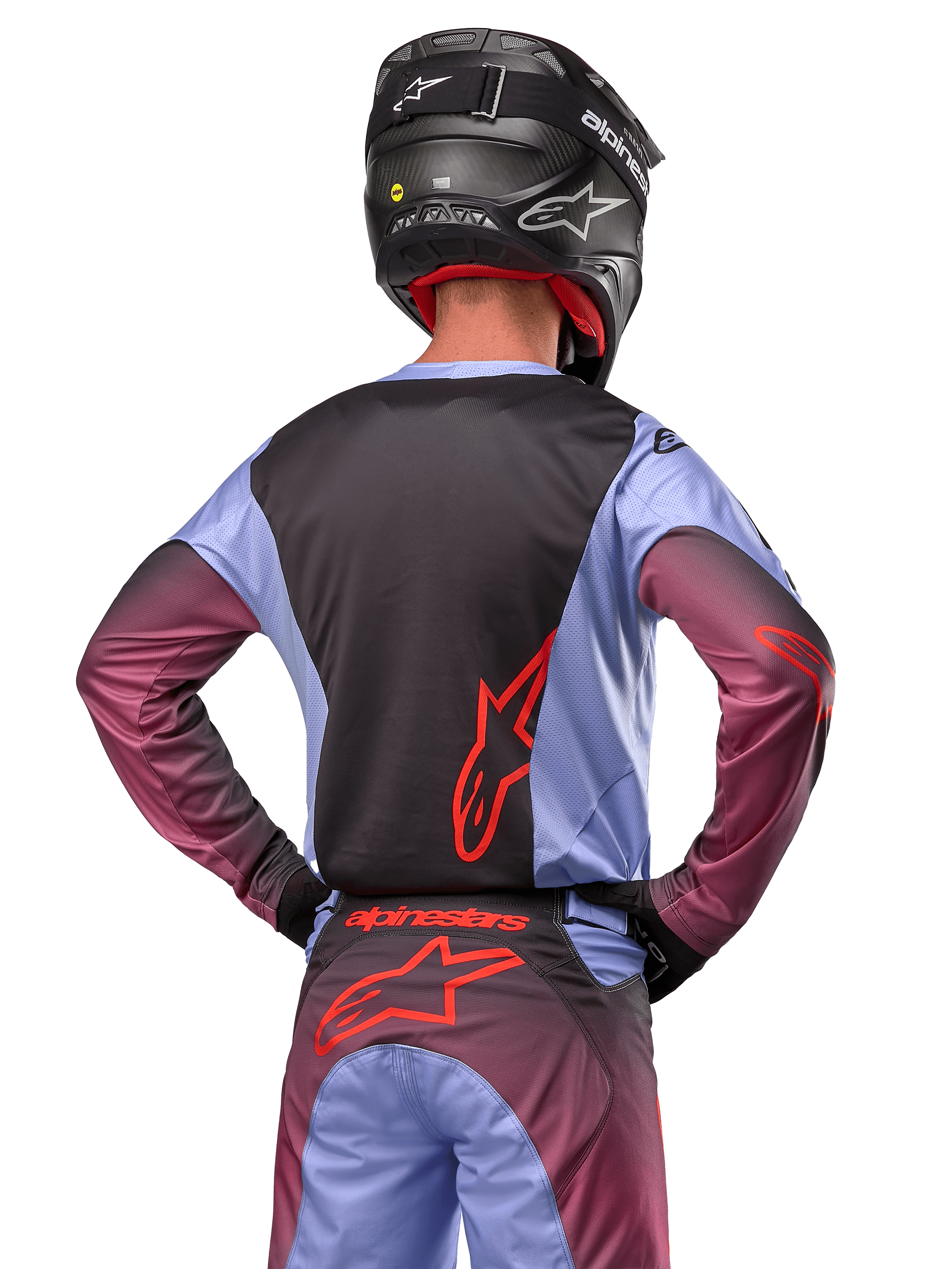 Zawodnik motocrossowy od tyłu w stroju Alpinestars 2024 Racer Hoen, fioletowo-czarna koszulka z czerwonym logo, pasujące spodnie z czerwonymi akcentami, czarny kask, dopasowany strój do wyścigów terenowych