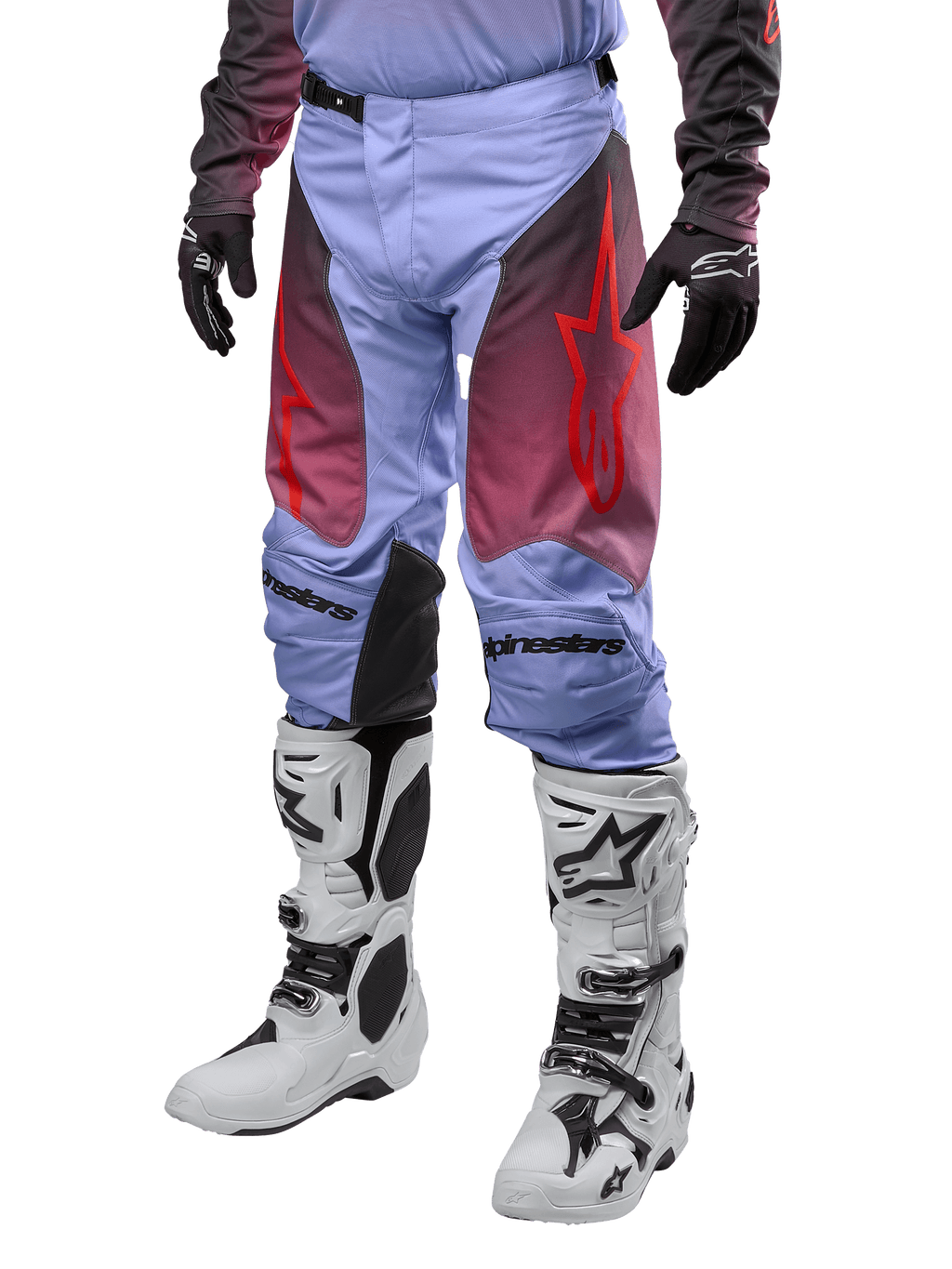 Alpinestars Racer Hoen Pants 2024, spodnie motocrossowe, fioletowe Lavan i czarne z czerwoną grafiką, czerwone logo gwiazdy na udach i czarne napisy na kolanach, noszone z biało-czarnymi butami i czarnymi rękawicami