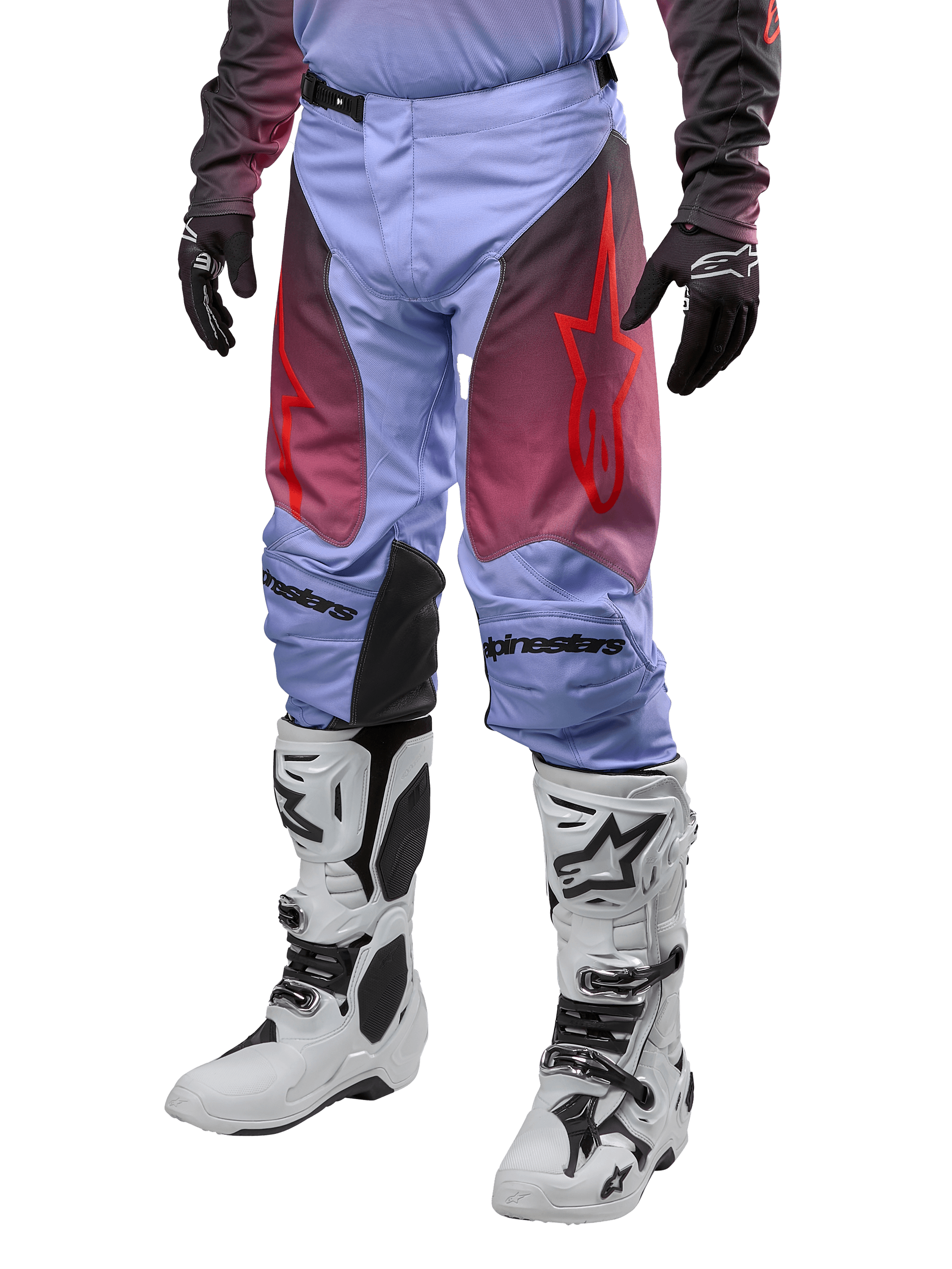 Alpinestars Racer Hoen Pants 2024, spodnie motocrossowe, fioletowe Lavan i czarne z czerwoną grafiką, czerwone logo gwiazdy na udach i czarne napisy na kolanach, noszone z biało-czarnymi butami i czarnymi rękawicami