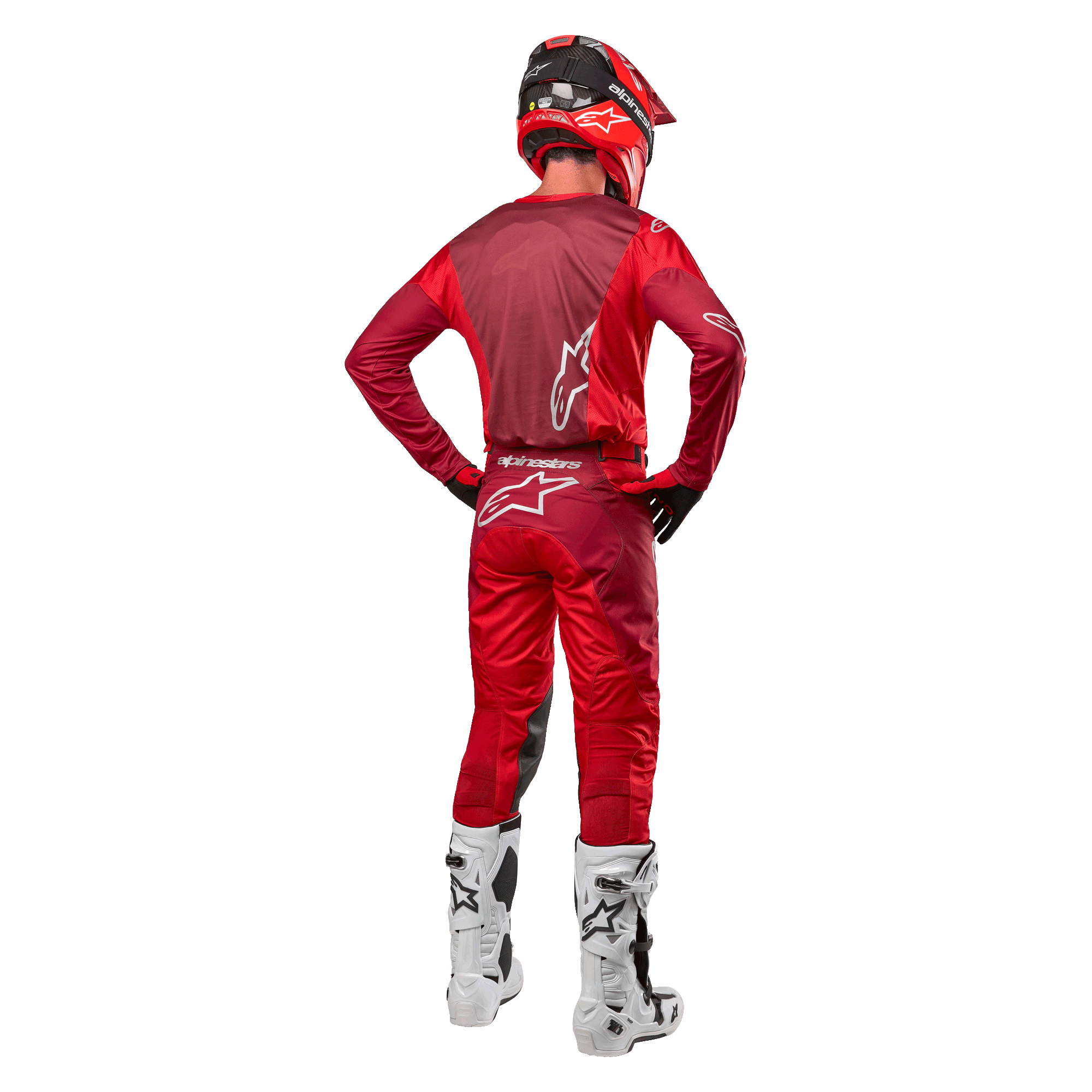 Spodnie Alpinestars Racer Hoen 2024 i dopasowana koszulka w kolorze Mars Red Burgundy, widok z tyłu zawodnika motocrossowego w pełnym stroju, w tym w czerwonym kasku i białych butach, prezentujący sportowy krój i branding do wyścigów terenowych.