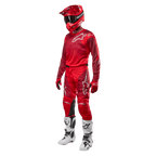Motocyklista motocrossowy w pełnym stroju wyścigowym, spodnie i bluza Alpinestars Racer Hoen 2024 w kolorze Mars Red Burgundy, czerwony kask, czerwone rękawice oraz biało-czarne buty, dopasowany zestaw do wyścigów terenowych