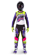 Zawodnik motocrossowy w pełnym stroju wyścigowym, bluza i spodnie Limited Edition Supertech Dirt Studios w kolorach białym, fioletowym i żółtym fluo, czarny kask z goglami, fioletowo-białe buty, dopasowany, wyrazisty komplet do wyścigów motocrossowych off-road